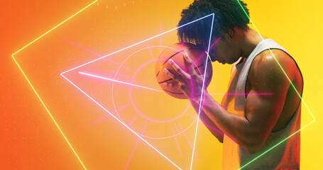 Naklejka premium Side view of biracial player with basketball standing over illuminated multiple geometric shapes