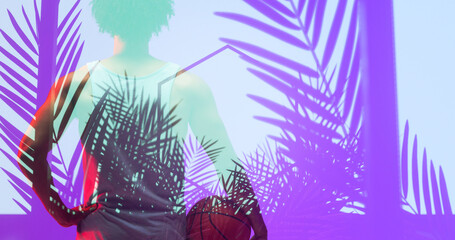 Naklejka premium Rear view of biracial basketball player with ball standing over illuminated hexagon and plants