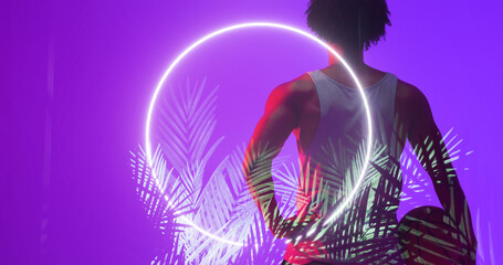 Naklejka premium Rear view of biracial basketball player with ball standing by circle and plants on purple background