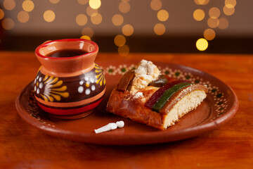 Slice of traditional rosca de reyes on a plate and coffee