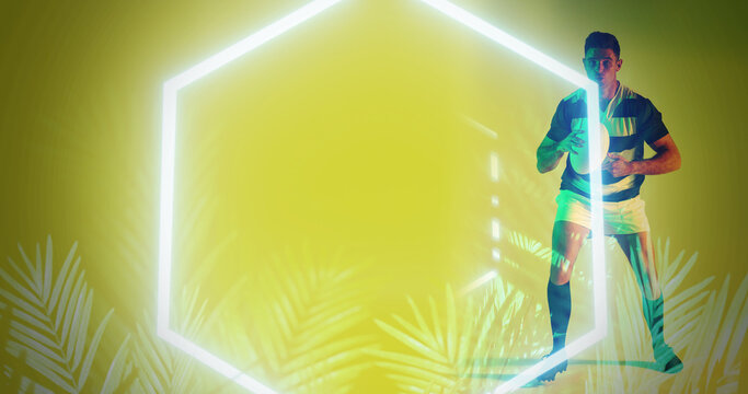 Illuminated hexagon and plants over caucasian rugby player holding ball on yellow background