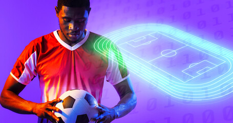 African american male player holding ball by illuminated soccer field over binary codes