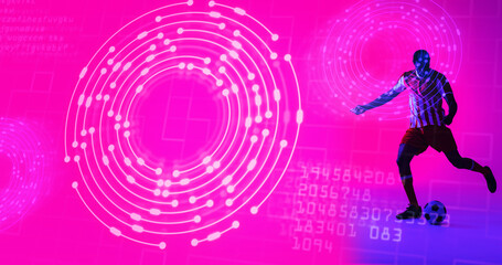African american male soccer player kicking ball over illuminated circles and computer language