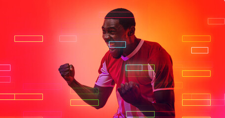 Cheerful african american male soccer player screaming and shaking fists over illuminated rectangles