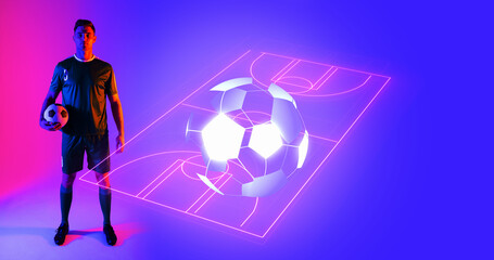 Caucasian young player with ball over neon soccer field against blue background, copy space
