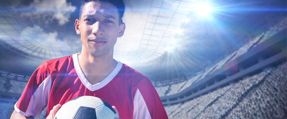 Portrait of confident biracial young soccer player with ball in stadium, copy space