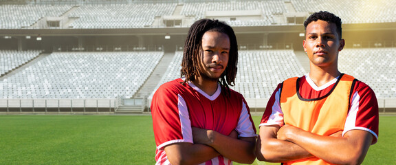 Obraz premium Portrait of confident multiracial young soccer players with arms crossed at stadium on sunny day