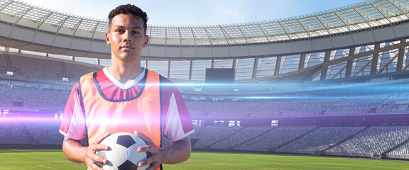 Portrait of confident biracial young player with ball on soccer field, copy space