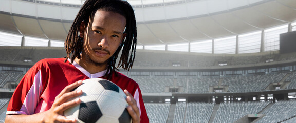 Image of biracial football player holding football in empty sports stadium