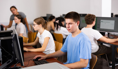Modern boy student learning basics of programming in group course in computer college