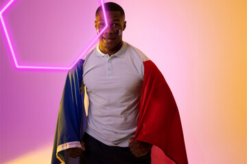 Hexagon neon over happy african american young male fan with france flag during match