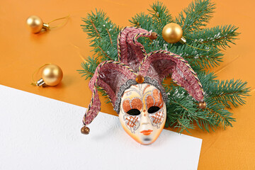 Christmas venetian mask with fir tree branch and invitation leaf on gold background
