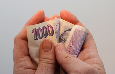 A woman´s hands are clutching a thousand Czech crown banknote