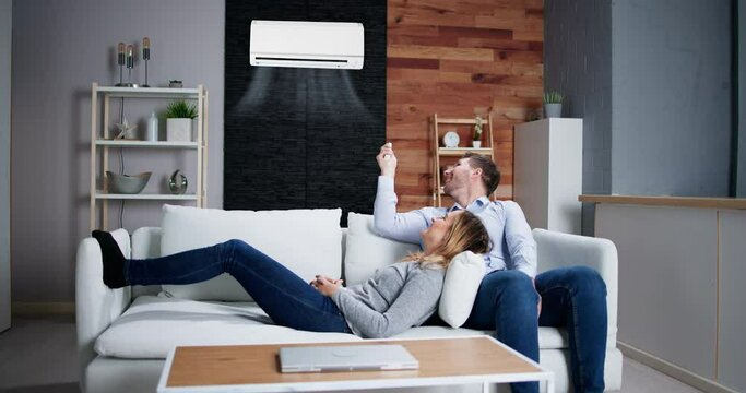 Happy Family Couple Using Air Conditioner