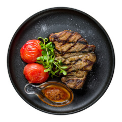 Fried pork loin with sauce and grilled tomatoes on black plate top view