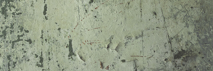 Obraz premium Peeling paint on the wall. Panorama of a concrete wall with old cracked flaking paint. Weathered rough painted surface with patterns of cracks and peeling. Grunge texture for wide panoramic background