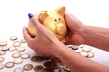 Woman's hand holding piggy bank and coins of the Brazilian money