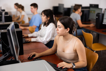 Teenage girl sitting at table and using computer during lesson.