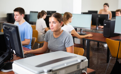Fototapeta premium Positive female teacher working on computer in school class