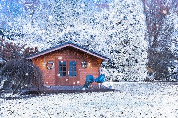 Wooden garden shed covered with snow. First snow. Winter in the garden