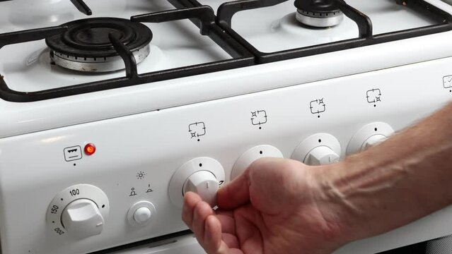  Hand turns shut off valve of gas stove burner and shuts off gas supply.