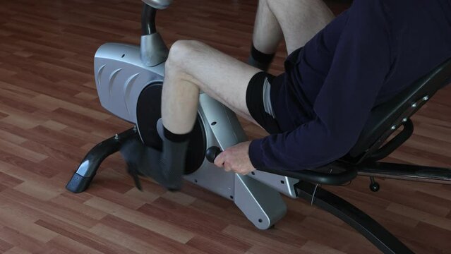 Closeup of legs pedaling exercise bike at home.
