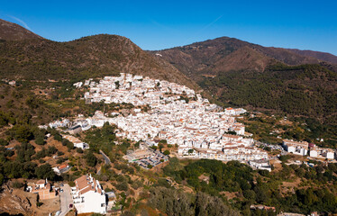 Fototapeta na wymiar View from drone of picturesque Spanish town of Ojen in green valley surrounded by Sierra Blanca and Sierra Alpujata mountan ranges on sunny fall day, Malaga province