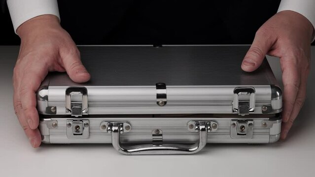 アタッシュケースに入った大量の1万円札の札束を見せるスーツを着た男性