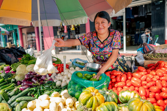 Retrato de mujer indigena viendo a Camara en su puesto de frutas y verduras en un mercado local. 