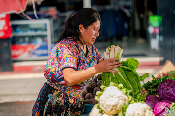 Mujer indigena sostiene en sus manos vegetales frescos en un mercado local de Guatemala.