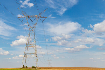 Electricity transmission towers in rural farm field. Electrical power grid and distribution safety,...