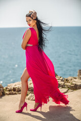 Girl in a long red dress enjoys the beach