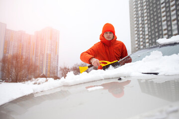 guy cleans the snow with a brush from the car, a man takes care of the car in winter