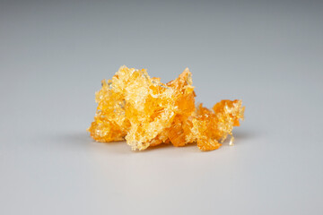 yellow wax piece with high THC on gray background