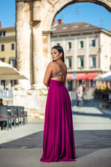 Beautiful young woman in a long dress enjoys a walk in the old part of the city