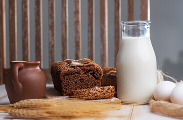 Black rye bread with raisins, homemade. Milk in a glass bottle, spikelets of rye and eggs on the kitchen table. Selective focus.