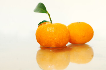 picture of two fresh small orange fruit with a reflection isolated on a white background studio shoot.