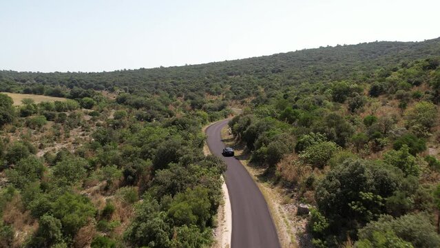 Black electric car driving on a round through vegetation France sunny day aerial 