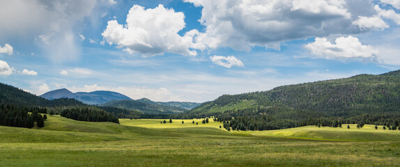 Panorama of a vast landscape of mountains and green meadows beneath a beautiful sky in the Valles Caldera National Preserve, New Mexico