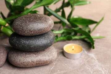 Stacked spa stones, bamboo and candle on light grey table, closeup