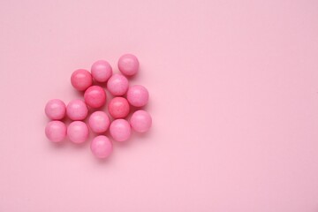 Many bright chewy gumballs on pink background, flat lay. Space for text