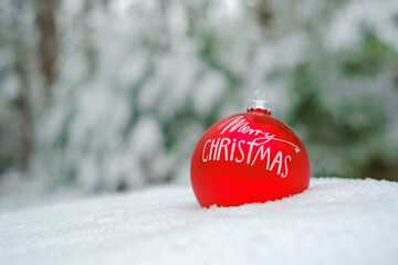 Merry Christmas .Red Christmas decorative ball i in the snow in a winter snowy forest.Holiday...
