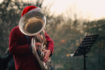 A musician wearing a Santa hat playing the saxophone.