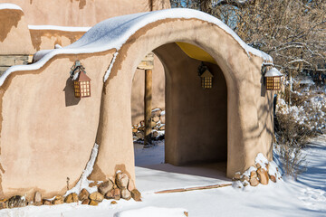Arched entrance in snow-covered adobe wall in Santa Fe, New Mexico