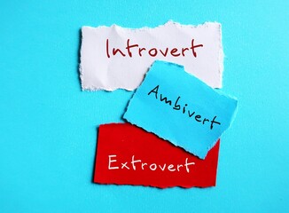 Torn paper on blue background with handwritten text - INTROVERT EXTROVERT AMBIVERT, Introverts tend to feel drained after socializing while extroverts tend to feel energized, ambivert is in the middle