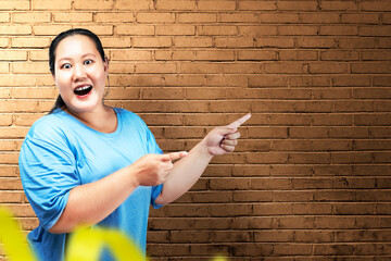 Asian fat overweight woman with an excited expression pointing to something