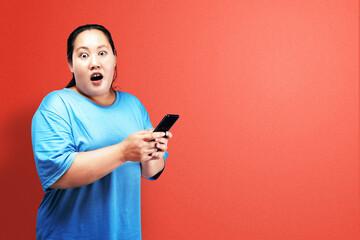 Asian fat overweight woman holding a mobile phone with a shocked expression