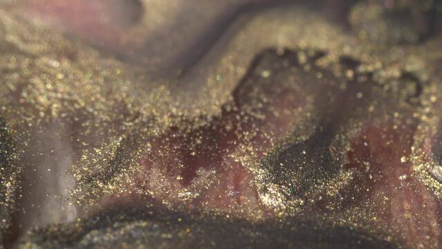 Holographic makeup cosmetics texture macro. Liquid Glitter gold and pink ink mix. Beautiful holiday multicoloured bokeh. Abstract background for Christmas