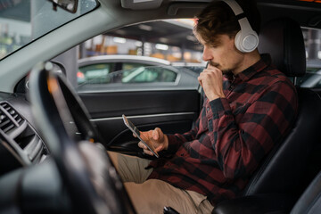 man with headphones listen music or podcast in car use mobile phone