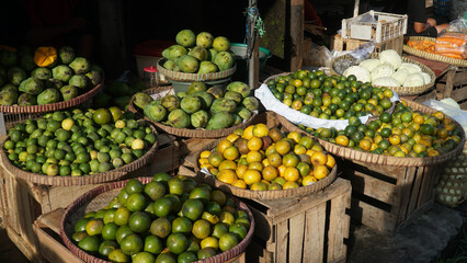 Oranges, limes and kaffir limes on a bamboo basket in a traditional market. Focus selected